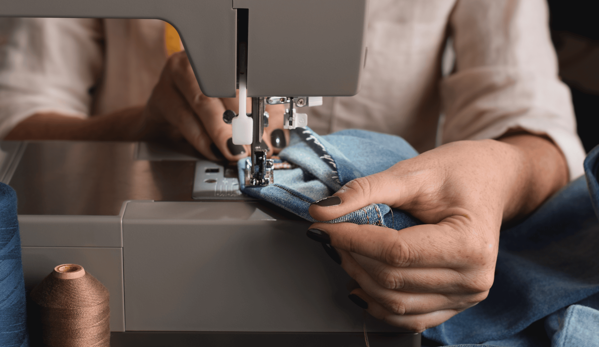 A woman is sewing a pair of jeans on a sewing machine.